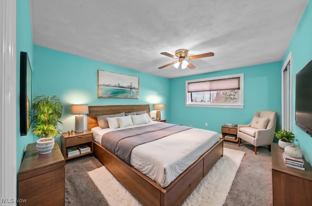 Bedroom with turquoise walls, a large wood bed, matching nightstands, and a cream lounge chair.