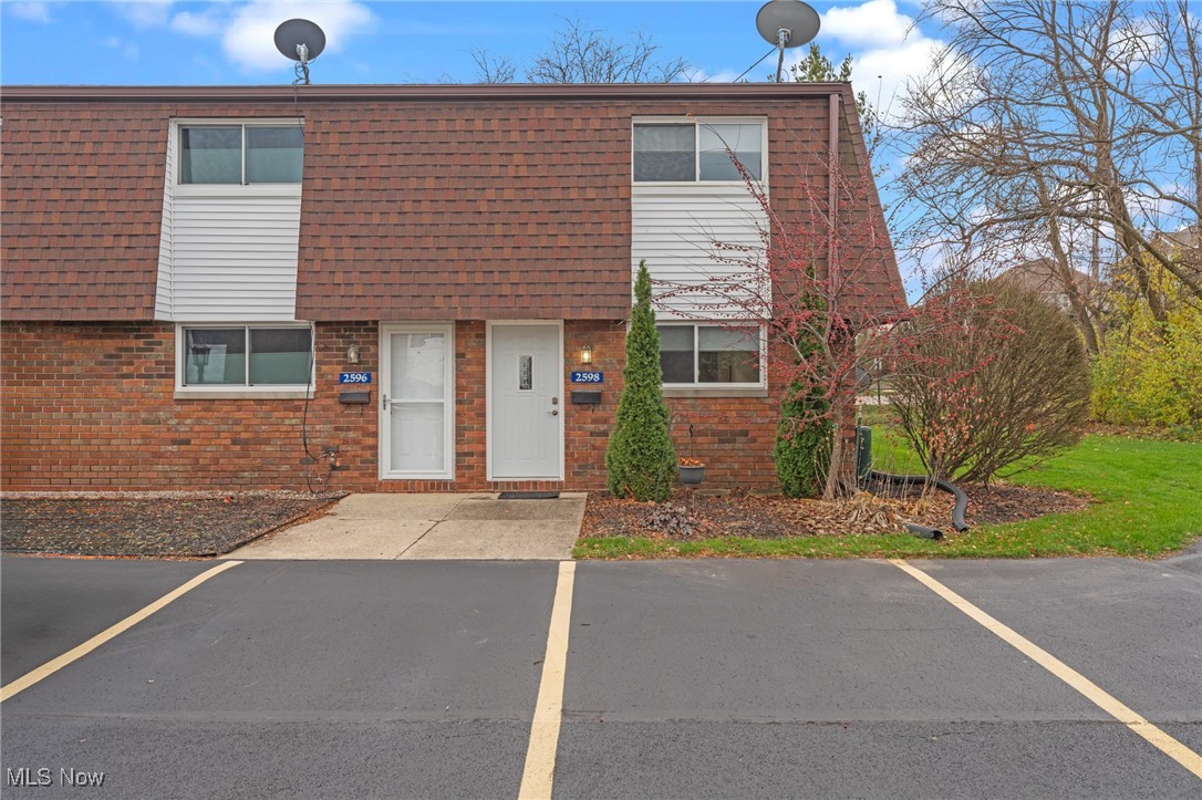 Brick townhouse exterior with two white entry doors and marked parking spaces in front.
