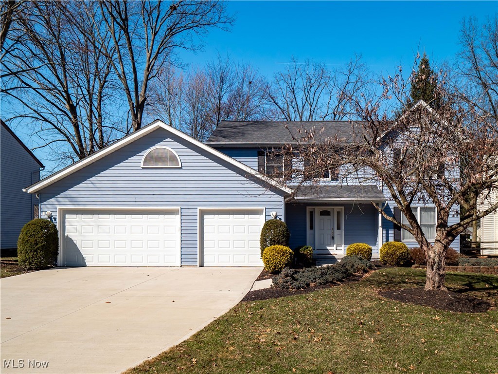 Blue two-story house with two white garage doors and a wide concrete driveway.