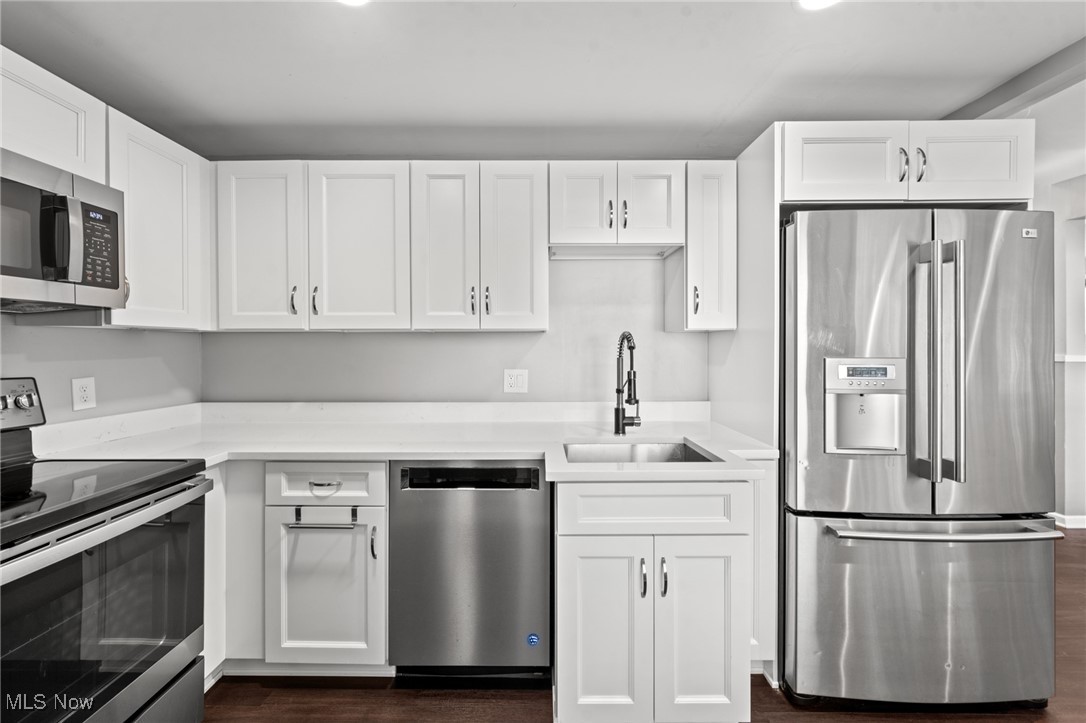 Kitchen with white paneled cabinets, stainless steel appliances, and a deep sink.