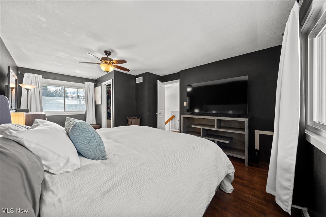 Bedroom with charcoal walls, a large white bed, and a wall-mounted television.