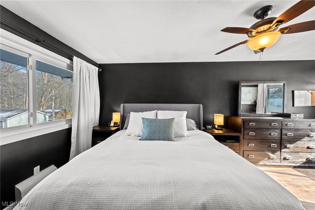 Bedroom with a white bed against a charcoal wall and a large window.