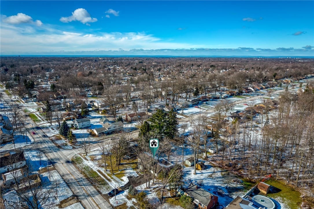 Aerial view of a snow-dusted neighborhood with the property marked and water on the horizon.