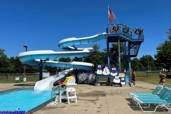 Outdoor pool with a large blue twisting waterslide and elevated tower.