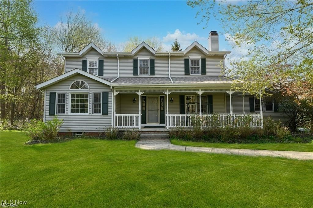 Gray two-story house with green shutters, a covered porch, and a broad front lawn.