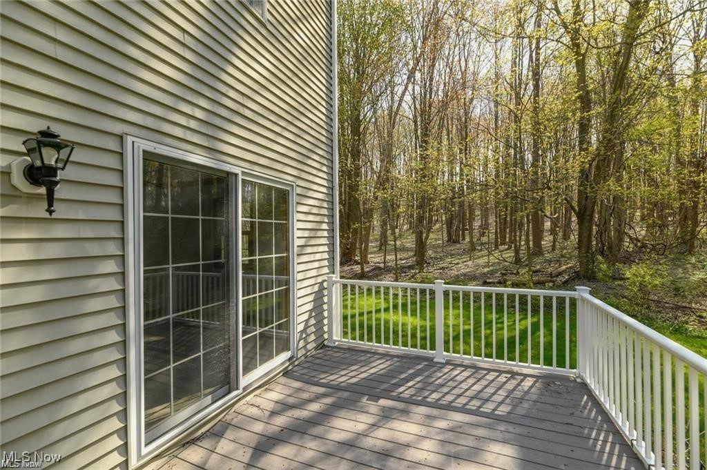 Raised deck with white railings overlooking a green lawn and wooded backyard.