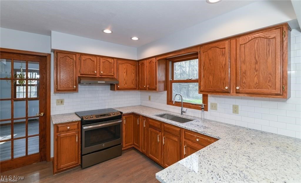Kitchen with wood cabinets, granite counters, subway tile backsplash, and a stainless steel range.