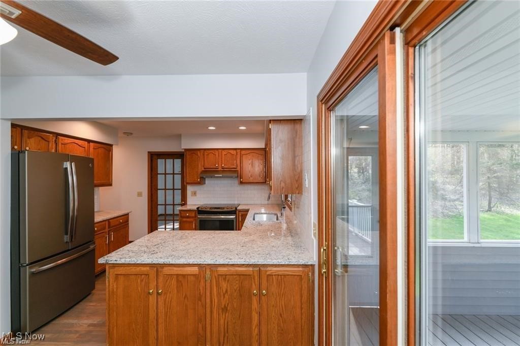 Kitchen with wood cabinets, a stone island, stainless appliances, and a glass door to the porch.