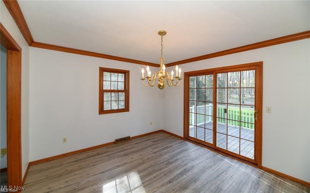 Empty dining room with a brass chandelier and sliding glass doors opening onto a deck.
