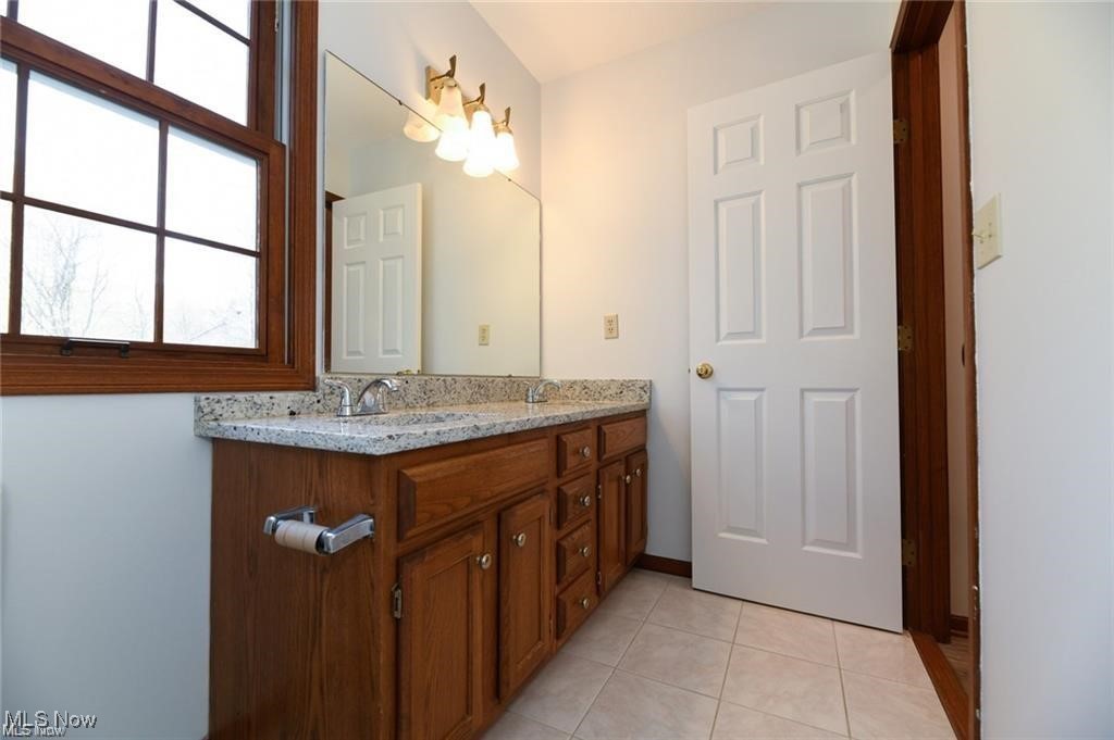 Bathroom with a long wood vanity, granite countertop, and large wood-framed window.