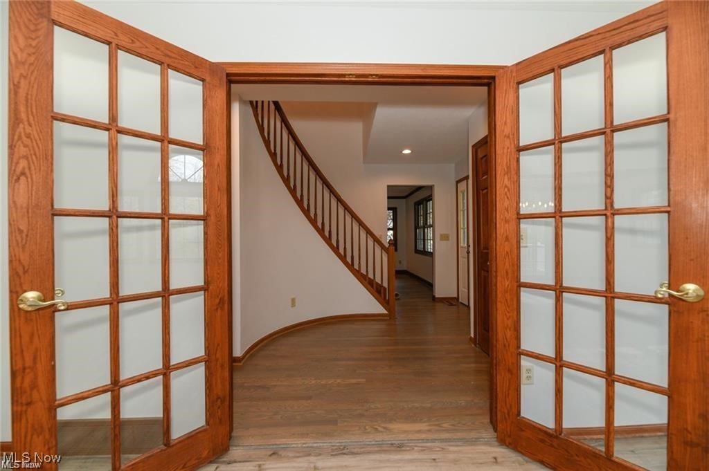 Entry foyer with hardwood floors, an open staircase, and glass-paneled French doors.