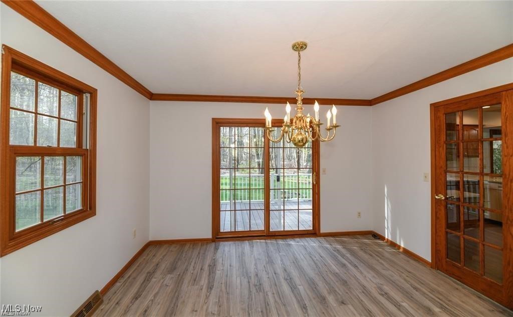 Empty dining room with a brass chandelier, wood trim, and glass doors to a deck.