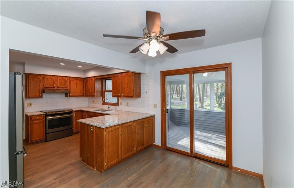 Kitchen with a granite-topped island, warm wood cabinets, and sliding doors to a wooded deck.