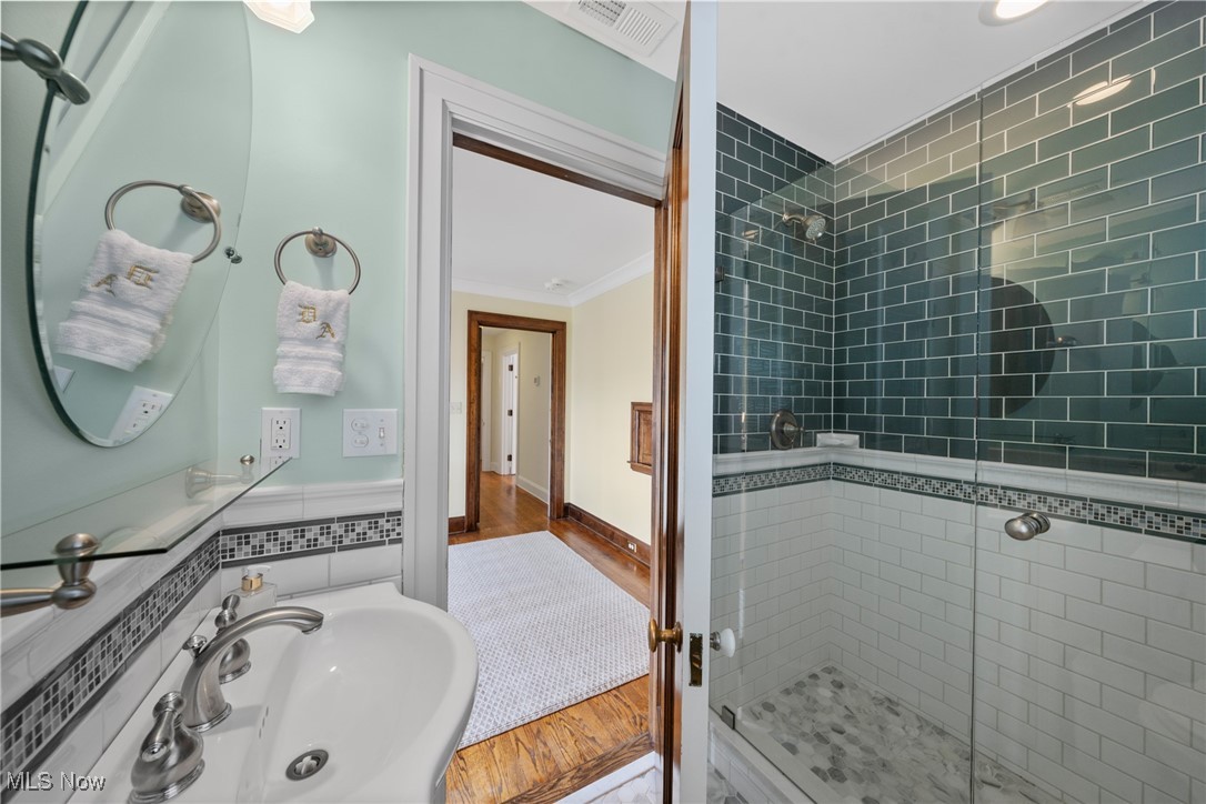 Bathroom with a glass-enclosed dark green tiled shower and white sink.