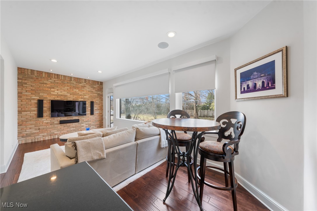 Living and dining area with a brick TV wall, hardwood floors, and a round high-top table.