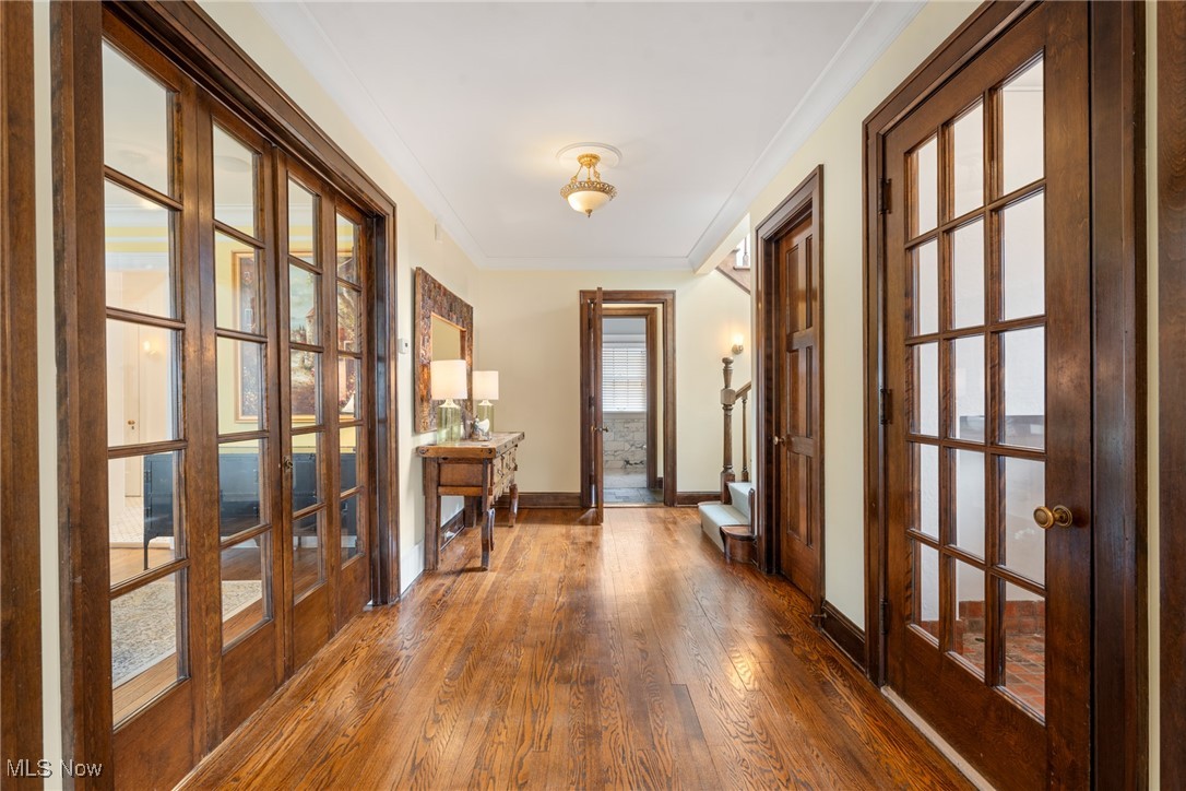 Hallway with polished hardwood floors, dark wood trim, and glass-paneled doors.
