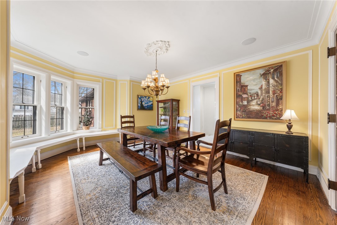 Dining room with yellow walls, a dark wood table, chandelier, and tall windows.