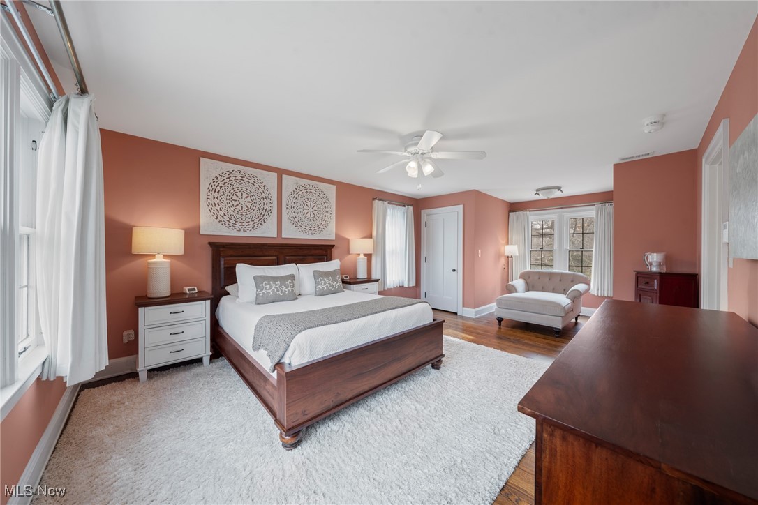 Furnished bedroom with coral walls, a dark wood bed, white rug, and window-side sitting area.