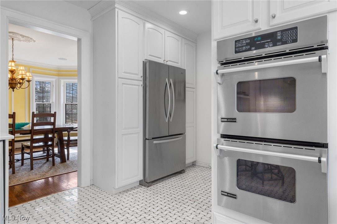 Kitchen with stainless-steel appliances, white cabinetry, patterned tile floor, and a doorway to the dining room.