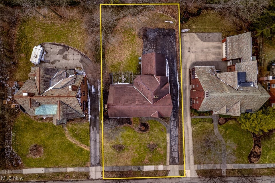 Aerial view of a house and lot outlined in yellow between neighboring homes.