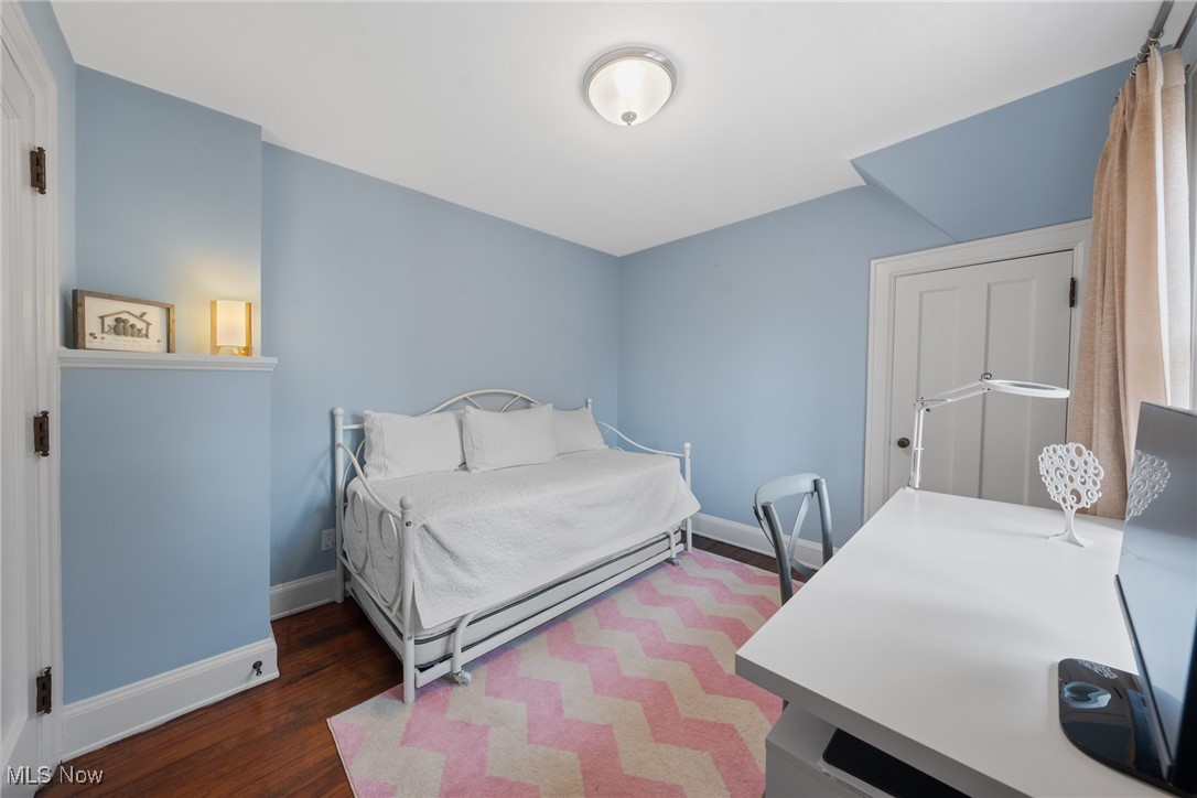 Blue bedroom with a white daybed, desk, and pink patterned rug.