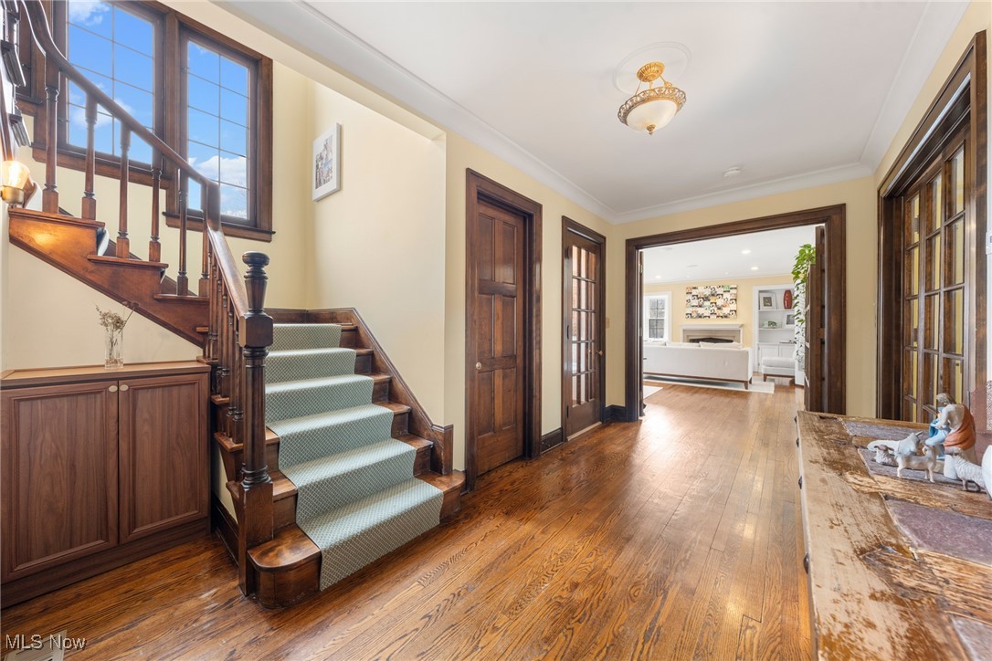 Foyer with a wood staircase, green runner, hardwood floors, and an adjoining living room.