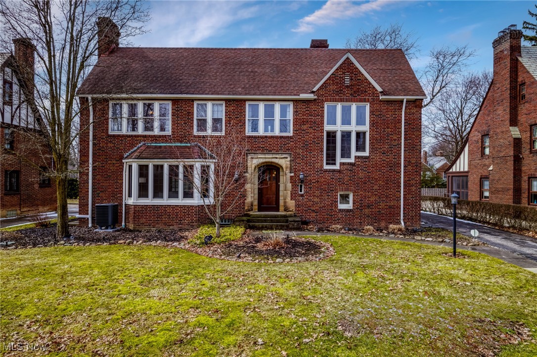 Two-story red-brick home with a stone-trimmed entrance and broad front lawn.