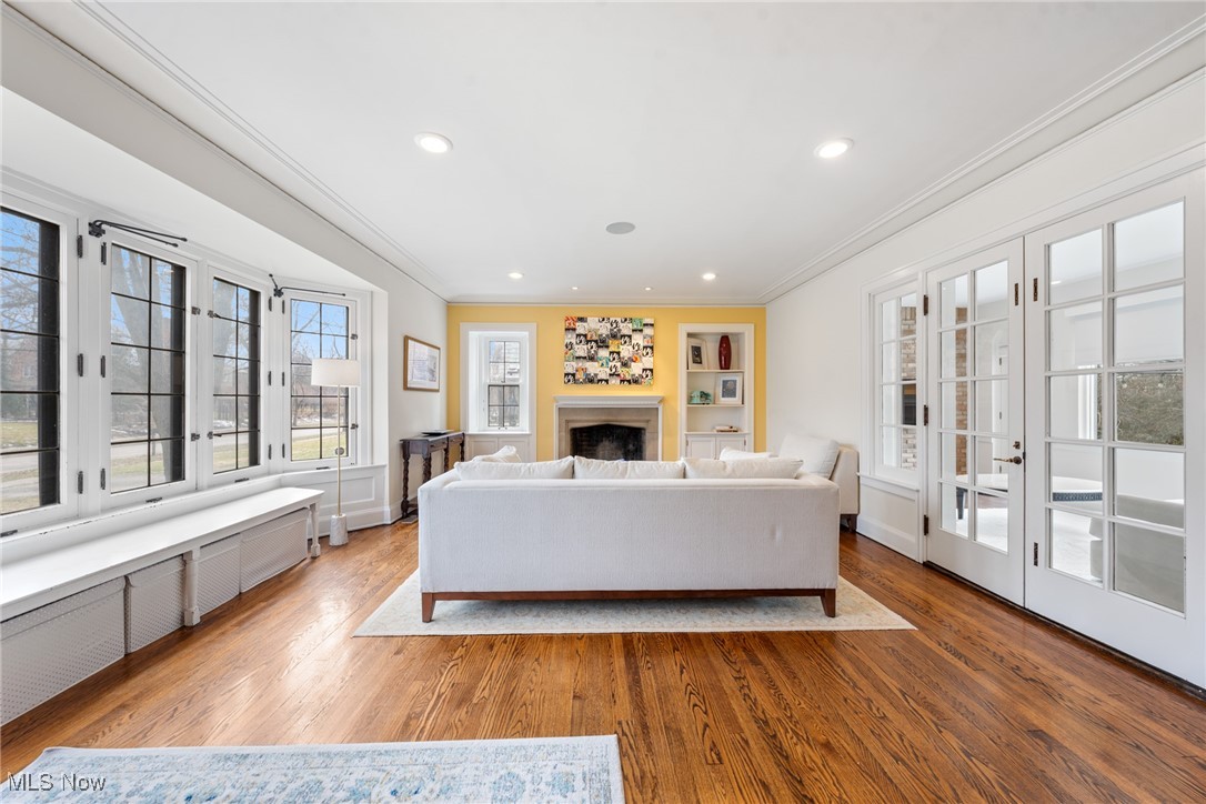 Living room with a white sofa, yellow fireplace wall, hardwood floors, and tall windows.