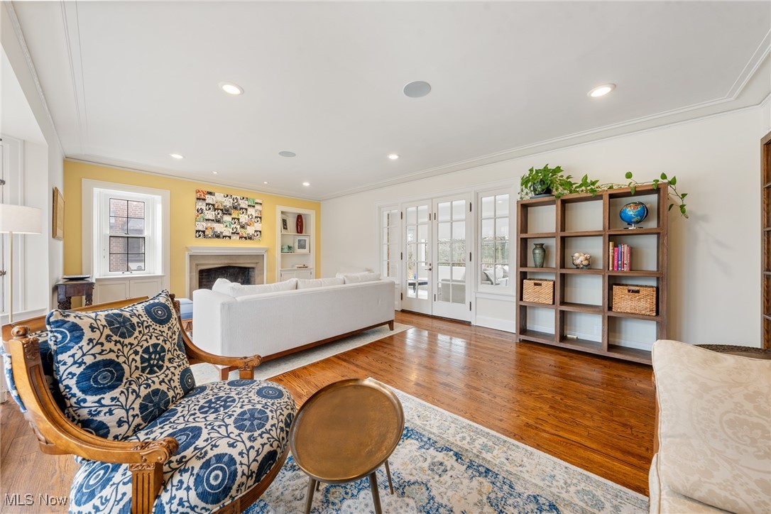 Furnished living room with a fireplace, French doors, and polished hardwood floors.