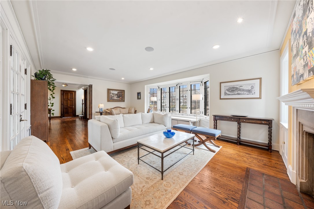 Living room with white sofas, blue-cushioned stools, large windows, and a fireplace.