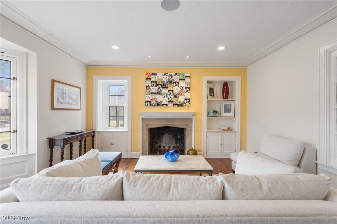 Living room with a white sectional, yellow fireplace wall, built-in shelves, and tall windows.