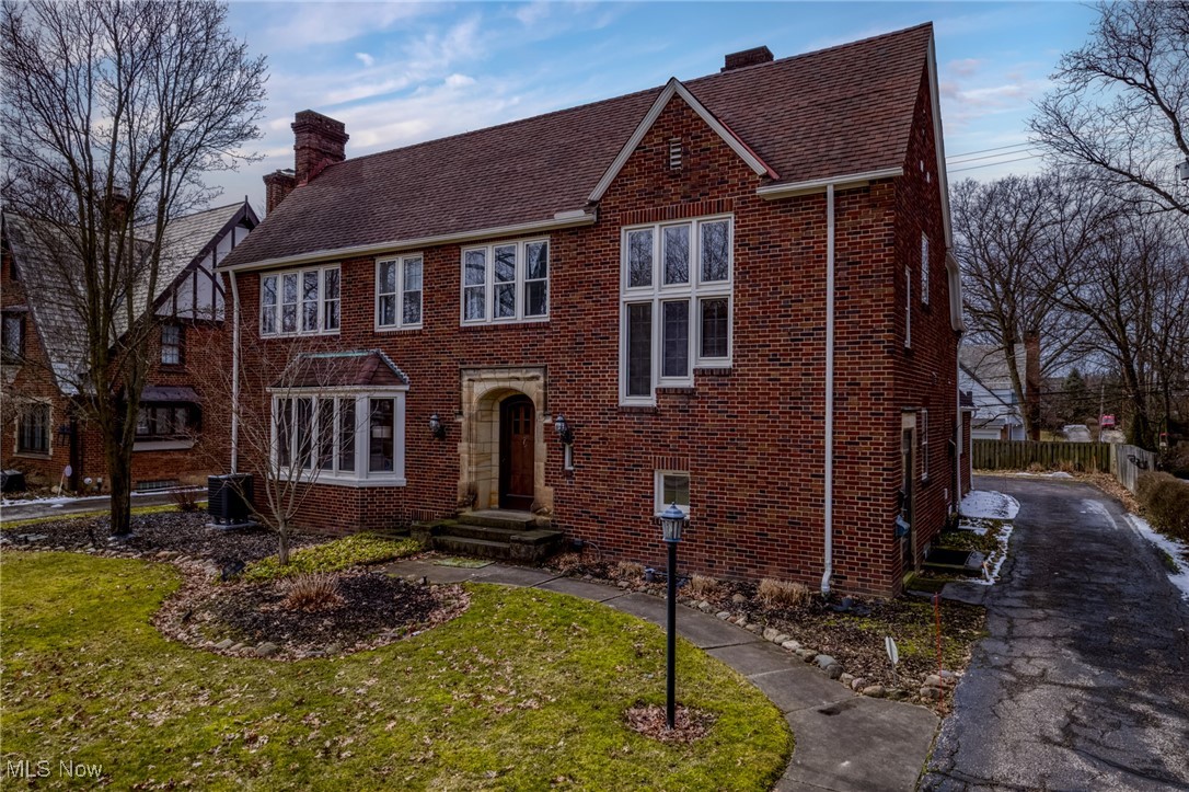 Red brick house with an arched stone entry, bay window, and side driveway.