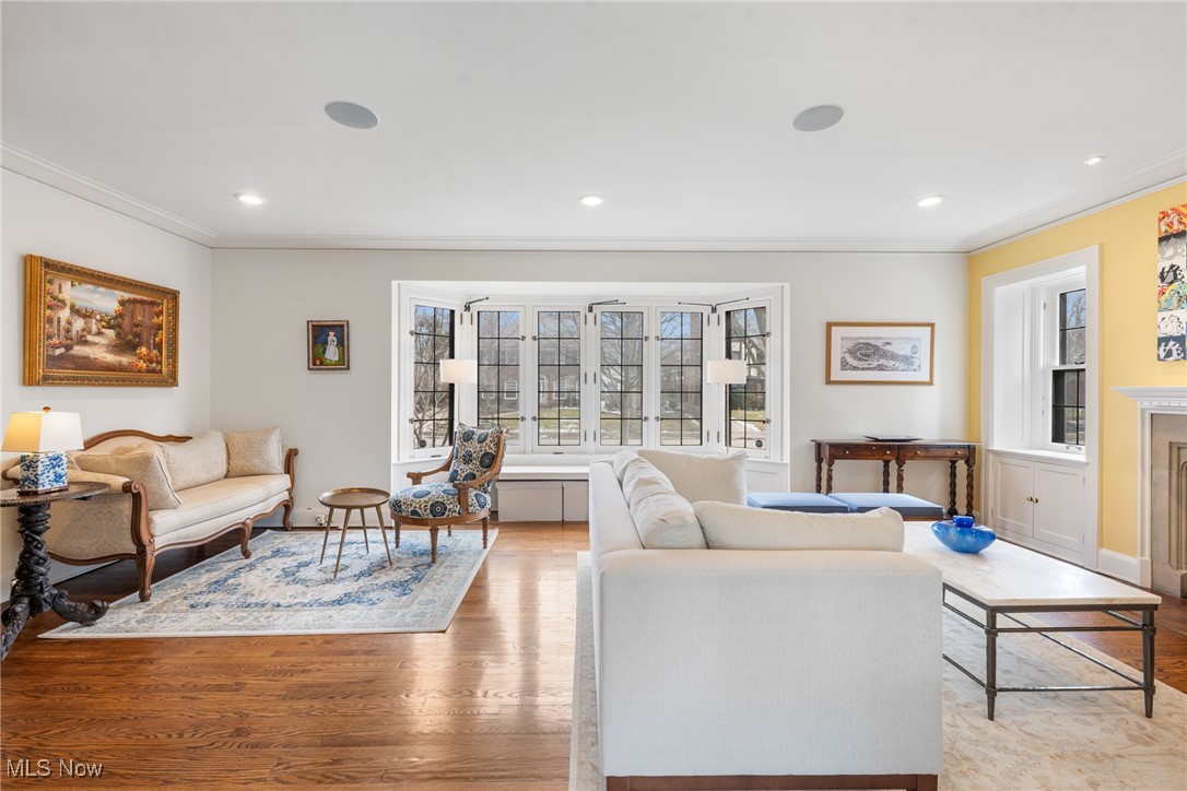 Living room with hardwood floors, cream sofas, a blue-and-white rug, and wide front-facing windows.