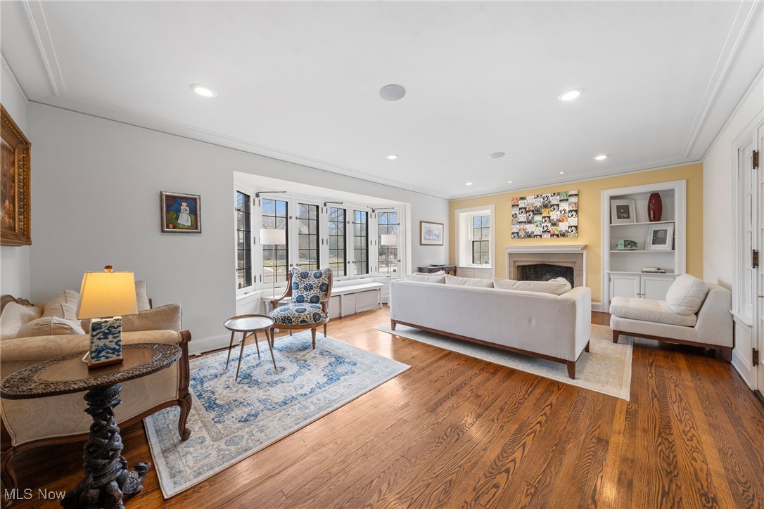 Living room with a fireplace, wide bay window, white sofa, and hardwood floors.