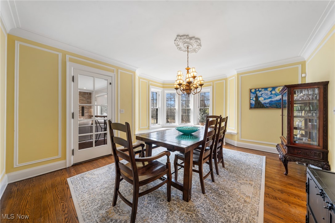 Dining room with yellow paneled walls, hardwood floors, a dark wood table, and bay windows.