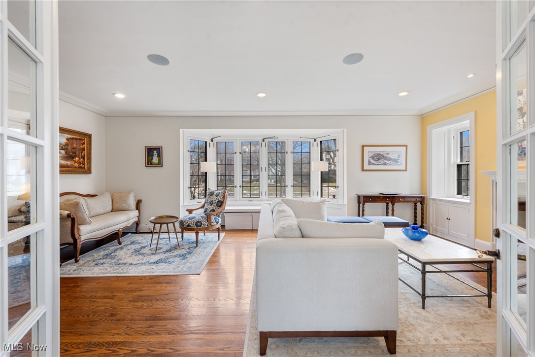 Living room with a wide bay window, hardwood floors, and white sofas.