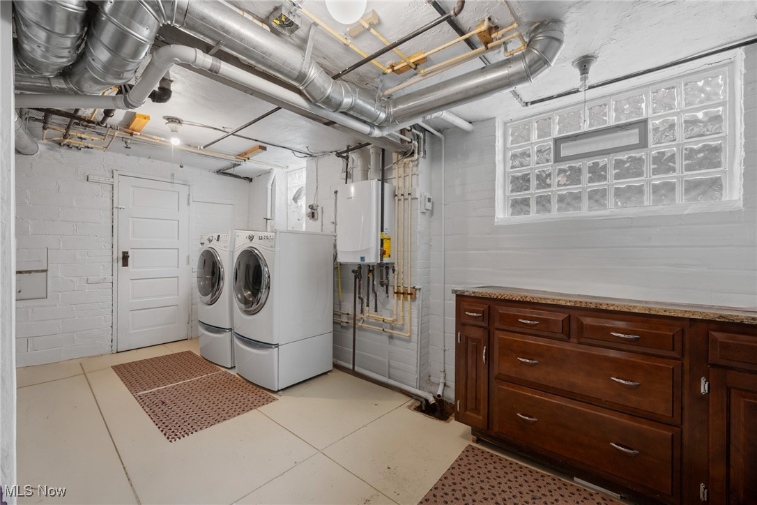 Basement laundry room with washer and dryer, exposed ductwork, and dark wood cabinets.