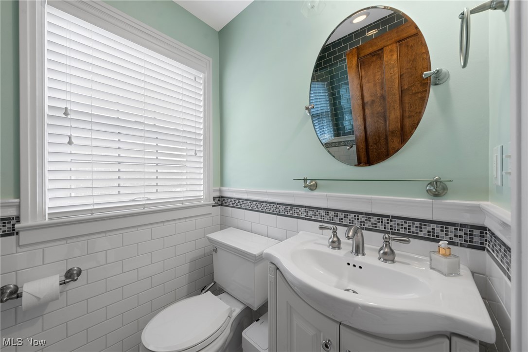 Bathroom with white vanity, oval mirror, subway tile, and a dark mosaic accent band.