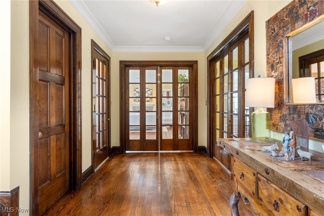 Hallway with dark hardwood floors, wood-paneled glass doors, and a carved wooden console table.