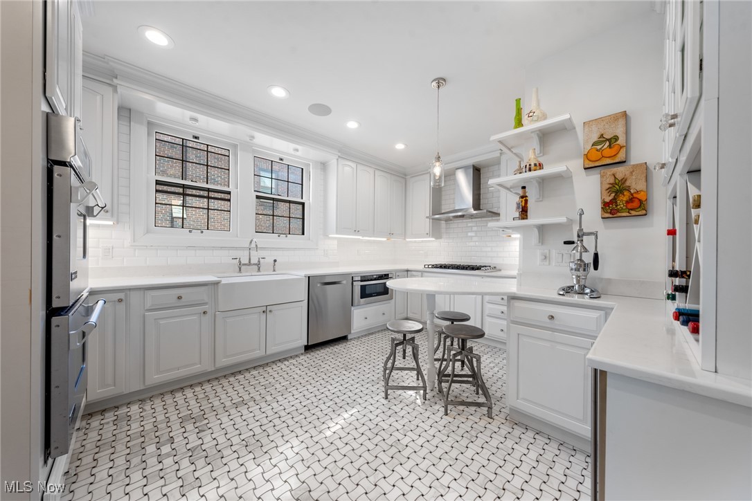White kitchen with a small island, stainless-steel appliances, and patterned black-and-white tile floor.