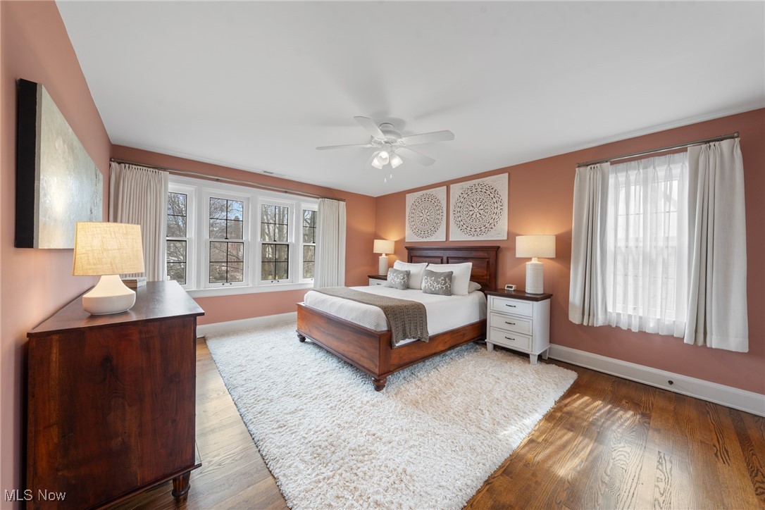 Staged bedroom with a dark wood bed, terracotta walls, curtained windows, and an ivory rug.