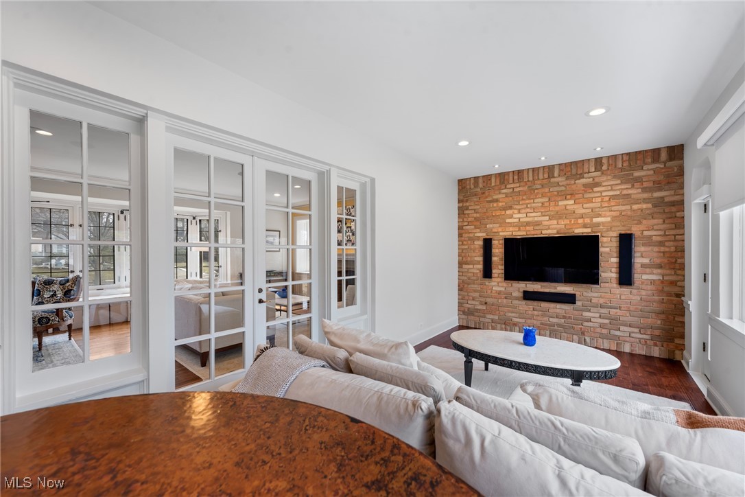 Living room with a white sectional and a television on a full brick accent wall.