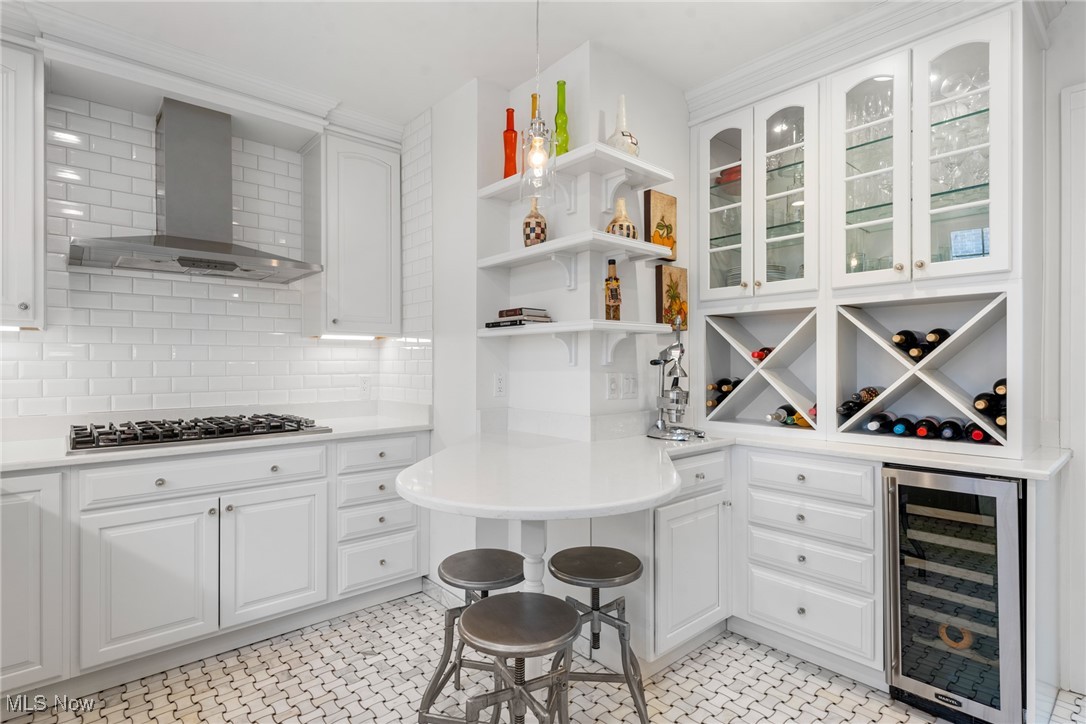 White kitchen with a rounded peninsula, glass-front cabinets, wine racks, and patterned tile floor.