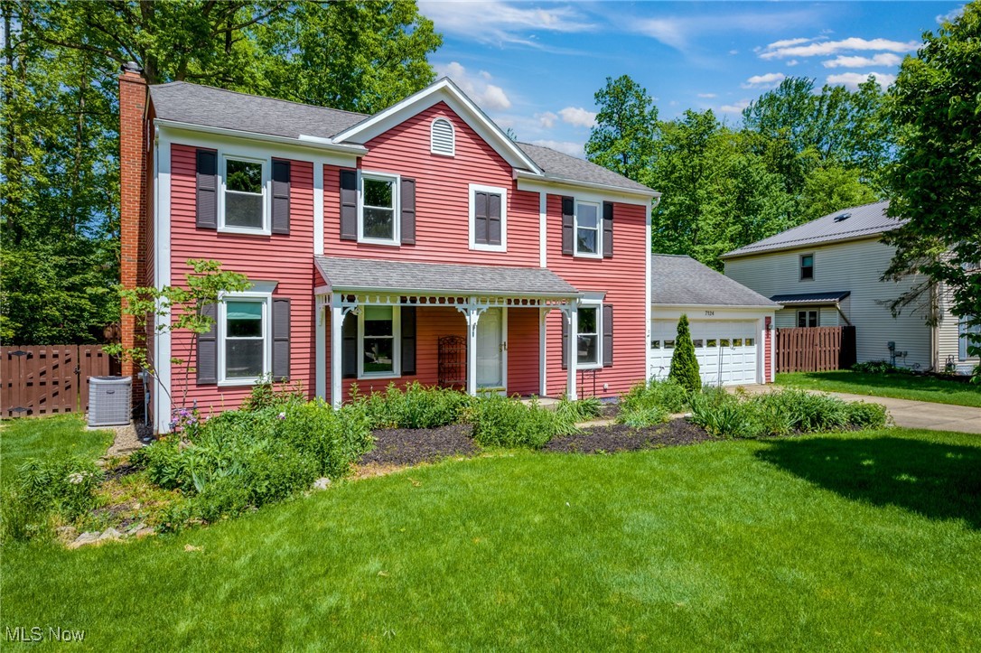 Red two-story house with a covered porch, attached garage, and landscaped front lawn.