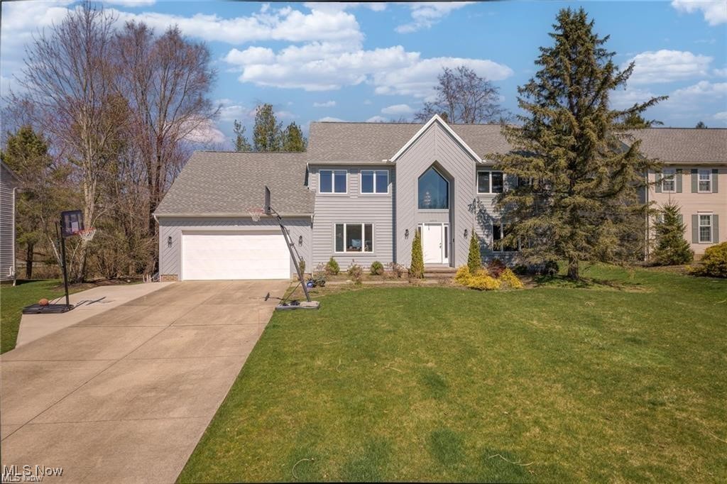 Two-story gray home with a peaked entry, attached garage, and basketball hoop beside the driveway.