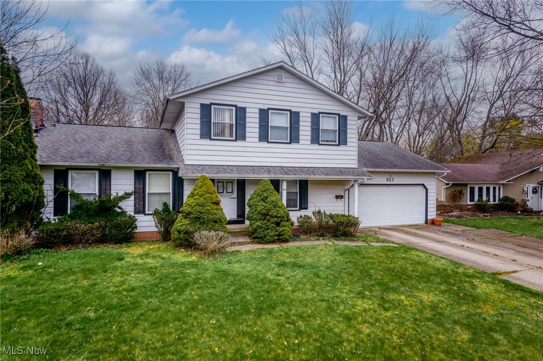White two-story house with attached garage, blue shutters, and front lawn.