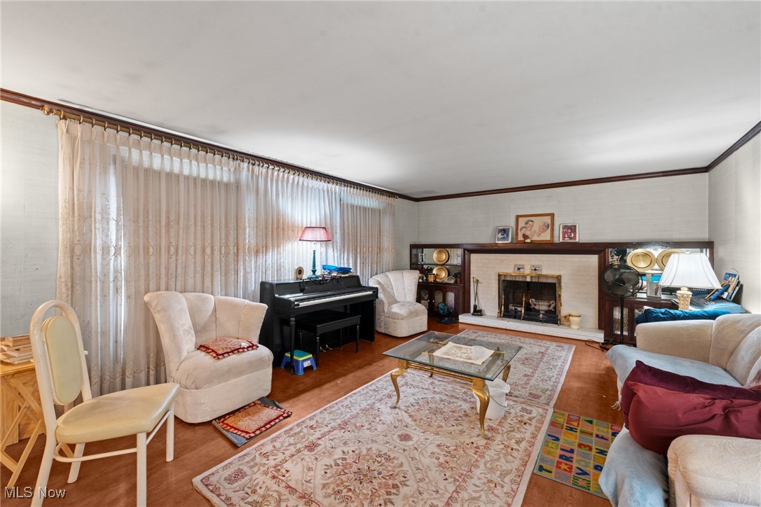 Furnished living room with a fireplace, piano, and large curtained windows.