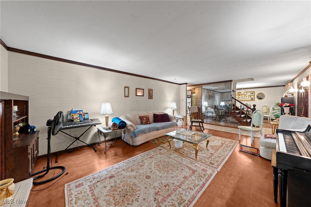 Living room with hardwood floors, patterned rugs, a piano, and a glass-walled dining area.