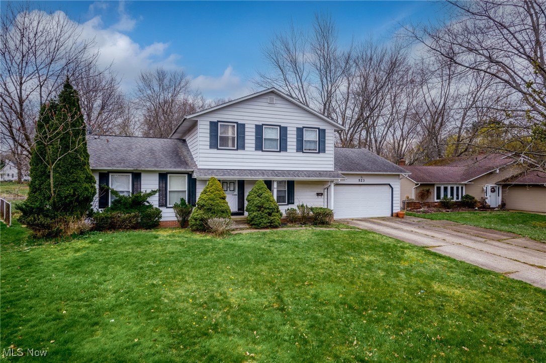 White two-story house with dark shutters, attached garage, and broad green front lawn.