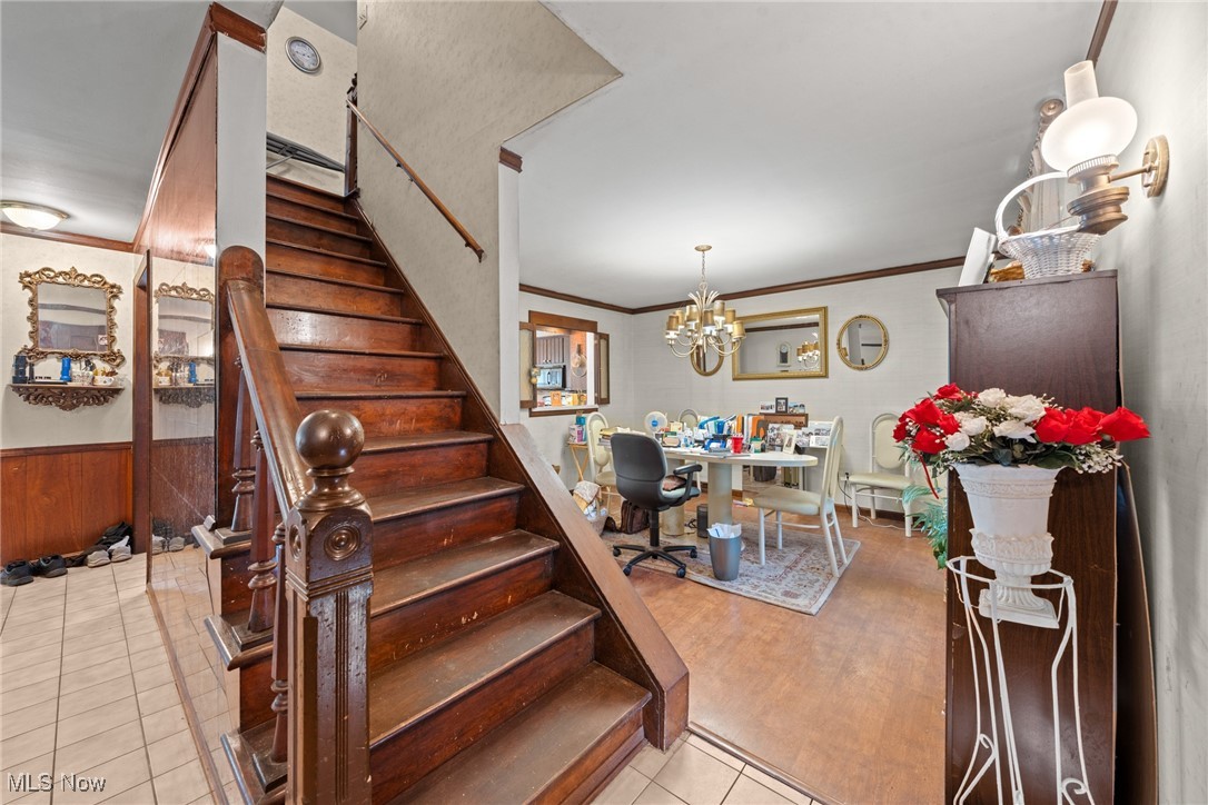 Entry hall with a dark wood staircase beside a furnished dining area.